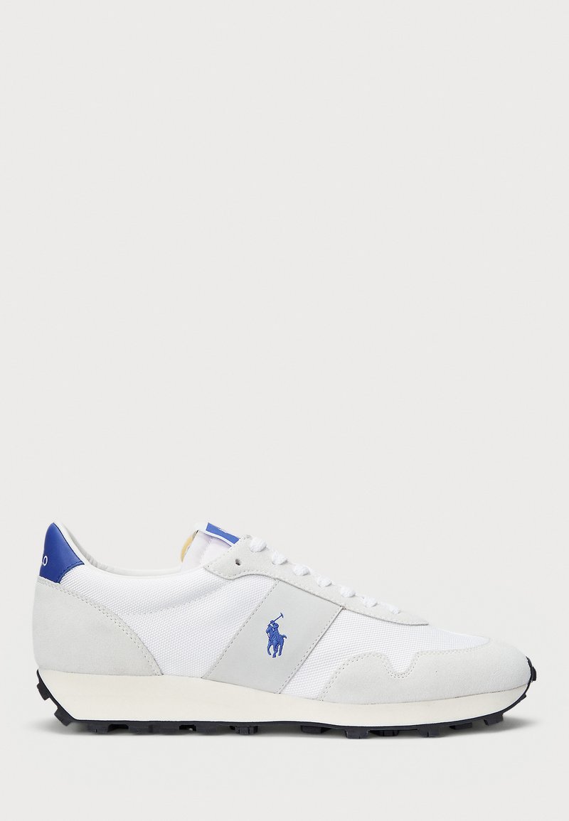 Λευκά αθλητικά παπούτσια με γκρι σουέτ λεπτομέρειες, διχτυωτό επάνω μέρος, μπλε ταμπά στην φτέρνα και μαυρό καουτσούκ σόλα. Διαθέτουν κλείσιμο με κορδόνια και λογότυπο.