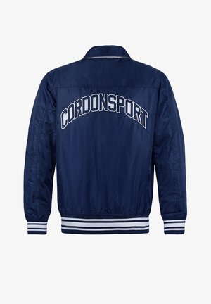 Navy blue bomber jacket with a satin finish, white striped cuffs and hem, and "CORDONSPORT" embroidered on the back in white letters.