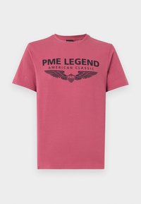 Camiseta de algodón rosa de manga corta, con un estampado gráfico negro que incluye "PME LEGEND" y detalles de alas.