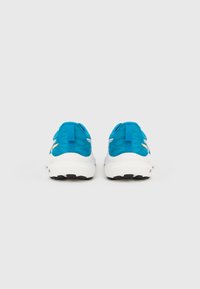 Blauwe sportschoenen met een bovenwerk van mesh en een witte zool, voorzien van zwart rubberen profiel en een gele accentdetail op de hiel.