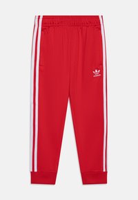 Pantalones deportivos rojos con cintura elástica, rayas laterales blancas y un logo bordado. Fabricados con un tejido suave y con puños ajustados.