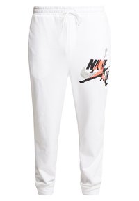 Bílé bavlněné tepláky s elastickým pasem a šňůrkou, na levém stehně potištěné vícebarevným logem Nike Air.