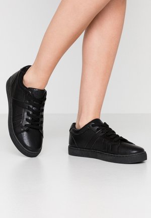 Černé kožené tenisky s texturovaným povrchem, s designem na šněrování, třemi akcentními pruhy a černou gumovou podrážkou.