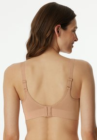 Nackenfreies, drahtloses Bustier mit verstellbaren Trägern, glatter Textur und Haken- und Ösenverschluss hinten. Schlichtes Design, keine Polsterung oder Verzierungen.