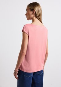T-shirt à manches courtes, rose pastel, avec un col rond et un tissu doux. Le design est décontracté et légèrement ample.