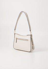 Sac à main beige avec une texture lisse, une forme incurvée, une seule bandoulière et une poche zippée à l'avant. Équipé de quincaillerie dorée et d'un bord noir.