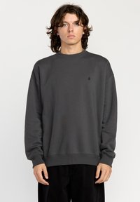 Gray crewneck sweatshirt made of soft fabric with ribbed cuffs and hem, featuring a small black logo on the chest and a relaxed fit.