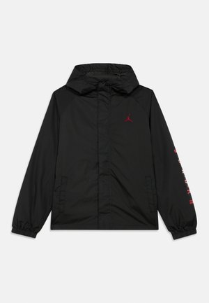 Sort hættejakke med frontlommer, rød Jordan-logo på brystet og rød skrift på højre ærme. Elastiske manchetter og lynlåslukning.