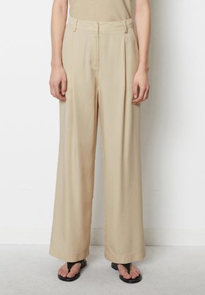Beige wide-leg trousers with a smooth texture, featuring a high waist, front pleats, and a straight cut. Worn with black sandals.