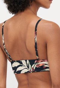 Floral-patterned bikini top with adjustable straps, featuring a navy background and green and pink accents, sleek and fitted design.