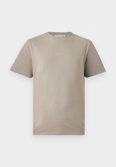 Μπεζ βαμβακερό κοντομάνικο T-shirt με στρογγυλή λαιμόκοψη και μικρό ετικέτα στο πίσω μέρος του λαιμού, εμπρός σε λευκό φόντο.