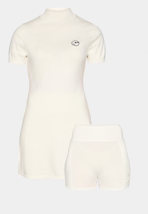 Vaalean ivory -värinen asu, joka koostuu lyhythihaisesta valekorkeakaula- cầu topista ja vastaavista shortseista. Topissa on pieni brodeerattu logo rinnassa.