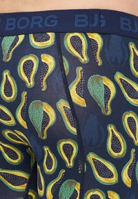 Blue boxer briefs with a patterned design featuring yellow, green, and black papaya shapes on a navy background. Soft, stretchy fabric.
