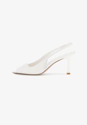 Witte leren slingback pumps met open teen en slanke hak, zijaanzicht op een witte achtergrond.