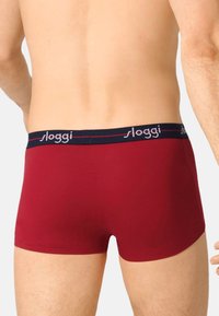 Punaiset puuvillaiset bokserishortsit tummansinisellä vyötärönauhalla, jossa hopeanhohtoinen "sloggi"-logo. Sileä pinta, vartalonmyötäinen malli, ilman lisäkuvioita.
