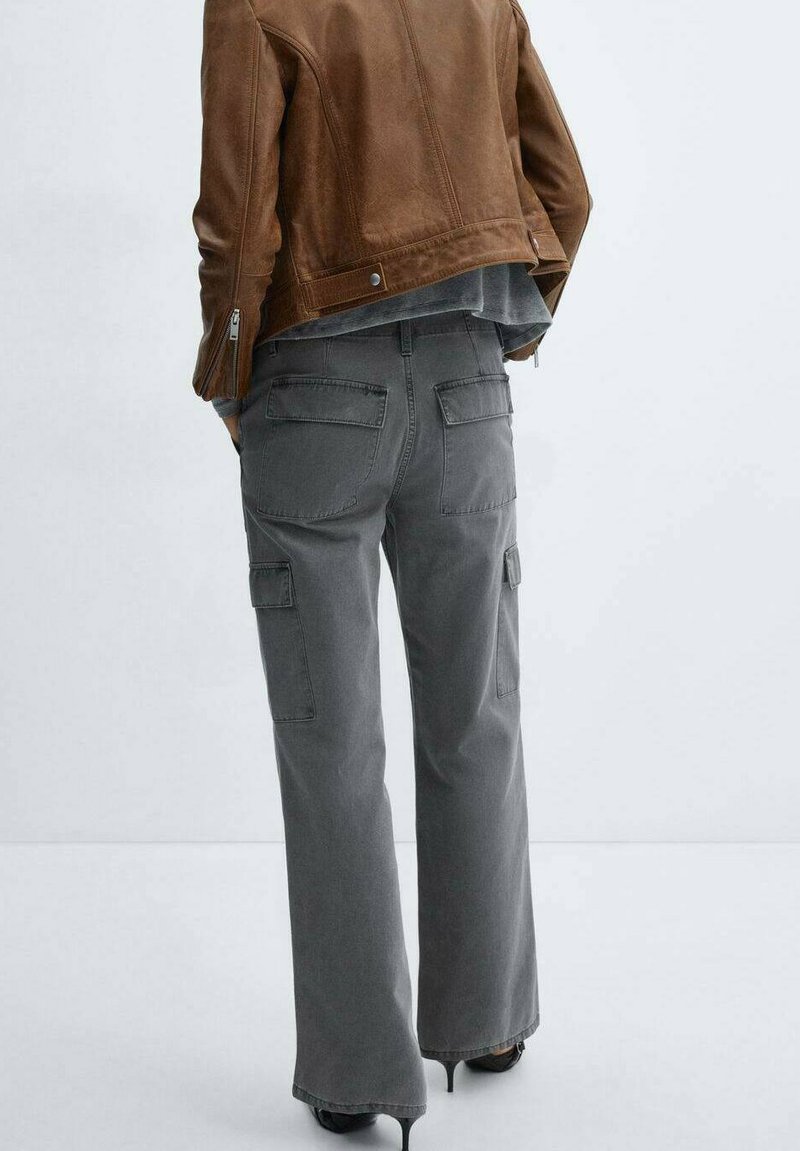 Szare spodnie cargo o szerokim kroju, wyposażone w liczne kieszenie i trwałą teksturę, połączone z brązową skórzaną kurtką.
