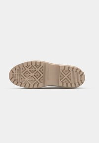 Semelle de chaussure en caoutchouc beige avec des motifs géométriques et des rainures profondes pour une bonne adhérence, marquée "CONVERSE" à l’arche.