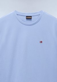 Light blue cotton t-shirt with a crew neck and a small embroidered Norwegian flag on the chest. Smooth texture, simple design.