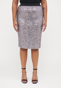 Zīda svārki gaisā purpursarkanā krāsā ar pieguļošu siluetu un elastīgu jostasvietu, apvienoti ar melniem siksnu papēžiem.