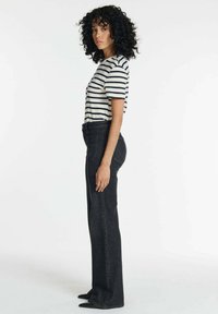 Zwarte hoge taille jeans met een rechte pijp en een subtiele textuur, gecombineerd met een gestreepte top met korte mouwen in crème en marineblauw.