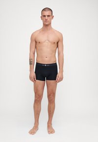 Boxers noirs en coton doux avec une coupe ajustée. Présentent une ceinture avec logo et une texture lisse.
