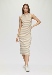 Gestreiftes Midi-Kleid in Beige und Weiß, aus geripptem Material; figurbetontes Design mit ärmellosem Schnitt und rundem Ausschnitt. Getragen mit hellbeigen Sneakers.