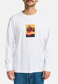Long-sleeve white cotton t-shirt featuring a colorful graphic of a skull with horns, accentuated by text and design elements.