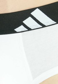 Witte sportondergoed met een zwarte elastische tailleband, voorzien van drie witte strepen en een textiel dat voor comfort zorgt.