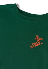 Roheline puuvillane T-särk ümmarguse kaelusega, mille esiküljel on oranž tikandiga logo ja graafiline disain. Pehme tekstuur, mugav stiil.