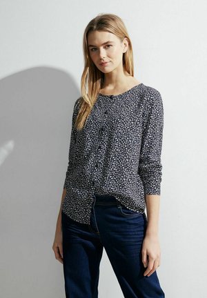 Langarm, knoopsluiting overhemd in marineblauw met een geometrisch wit patroon. Zachte stof met een relaxte pasvorm en ronde halslijn. Gecombineerd met donkere jeans.