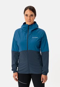 Veste coupe-vent bleu et marine avec capuche, fermeture éclair à l'avant, poches latérales et silhouette ajustée, fabriquée en tissu léger et lisse.