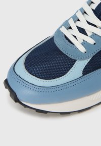 Μπλε αθλητικό παπούτσι με επάνω μέρος  από δίχτυ, σουέντ λεπτομέρειες και λευκά κορδόνια. Στρογγυλερή μύτη, αντιθετική λαστιχένια σόλα με υφή για καλύτερη πρόσφυση.