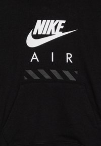 Zwarte sweatshirt met witte "NIKE" logo en "AIR" tekst. Heeft een zak en zwarte diagonale strepen als ontwerpdetail. Zachte stofafwerking.