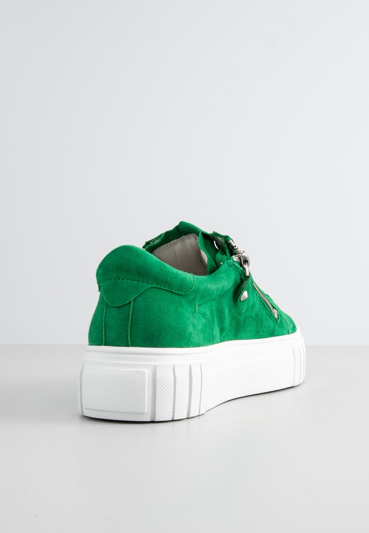 Grüne Wildleder-Sneaker mit einer weißen Gummisohle, seitlichen Reißverschlüssen und minimalen Nähten. Die Rückseite hat ein abgerundetes Design und eine weiche Textur.