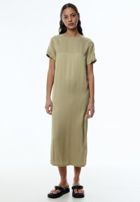 Olivgrünes, knielanges Kleid aus glattem Stoff mit kurzen Ärmeln. Minimalistisches Design mit geradem Schnitt und rundem Ausschnitt.