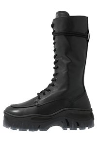 Czarne skórzane wysokie buty za kolano z masywną, fakturowaną podeszwą, zaokrąglonym noskiem i sznurowanym przodem. Posiadają solidne przeszycia i metalowe oczka.