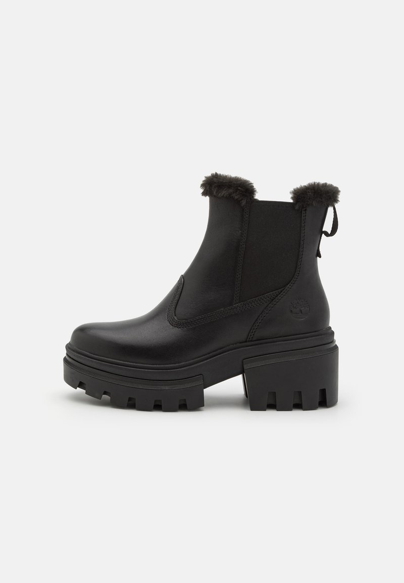 Botines negros de cuero suave con un puño de pelo texturizado, paneles elásticos laterales y una suela de plataforma gruesa con profundos surcos.