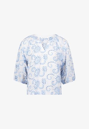 Hvid bluse med lyseblå blomsterbroderi, korte puffede ærmer og V-hals. Har et indviklet broderet mønster og huller i stoffet som dekorationer.
