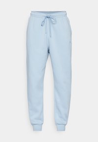 Světle modré tepláky vyrobené z měkké látky, se elastickým pasem na šňůrku a malým vyšitým logem na boku.