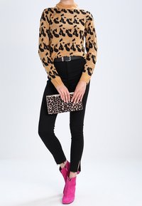 Gebreide trui in bruin met zwart luipaardprint, zwarte skinny jeans, roze enkellaarsjes en een luipaardprint clutch.