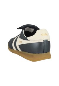Scarpa da ginnastica Gola in bianco e nero con suola in gomma, vista dal lato posteriore destro e parte superiore aperta con etichetta della taglia visibile all'interno.