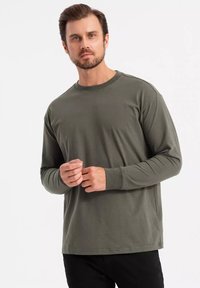 T-shirt a maniche lunghe e collo rotondo in verde oliva scuro, realizzata in cotone morbido, con una vestibilità rilassata e una texture liscia e semplice.