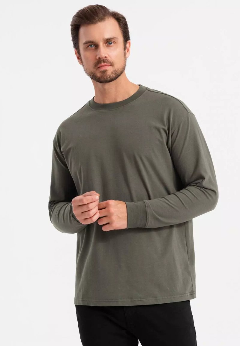 T-shirt a maniche lunghe e collo rotondo in verde oliva scuro, realizzata in cotone morbido, con una vestibilità rilassata e una texture liscia e semplice.