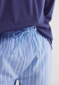 Lichtblauwe gestreepte pyjamabroek met een elastische tailleband en trekkoord. Gekocht met een marineblauw geribbelde top, de stof lijkt zacht en ademend.