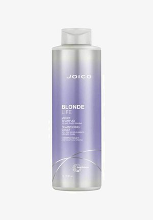 Violetti shampoo kirkkaassa muovipullossa, jossa on viettelevä laventeliharmaa gradienttisuunnittelu. Pullossa on valkoista tekstiä ja pyöreä logo pohjassa.