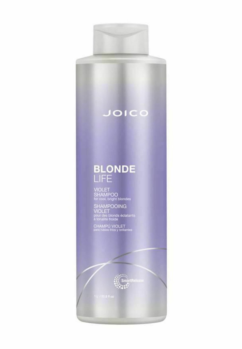 Lila shampoo i en klar, cylinderformad flaska med en gradient från silver till lavendel. Med vit text och en silvervirveldesign.