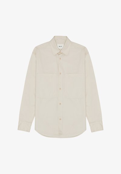 Lys beige langærmet skjorte lavet af blødt stof, der har en spidse krave, forreste knapper og to brystlommer. Lige nederste kant design.