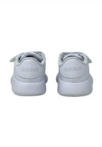 Sneakers bianchi Adidas con materiale liscio, forma arrotondata e piccola striscia in velcro. Il logo è impresso sul retro.