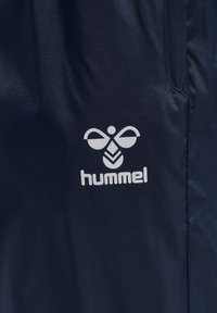 Marinblått tyg med en slät textur, med en vit logotyp och texten "hummel" på nedre högra sidan.