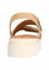 Beige sandal with multiple cross straps, flat platform sole, and smooth surface texture. Neutral color and simple design enhance versatility.